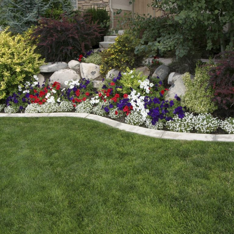 Colourful flowerbeds with various plants, rocks, and a well-manicured lawn.